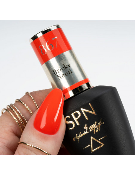 Butelka z lakierem hybrydowym i kciuk pomalowany neonowym czerwonym kolorem Butelka z lakierem hybrydowym i kciuk pomalowany neonowym czerwonym kolorem