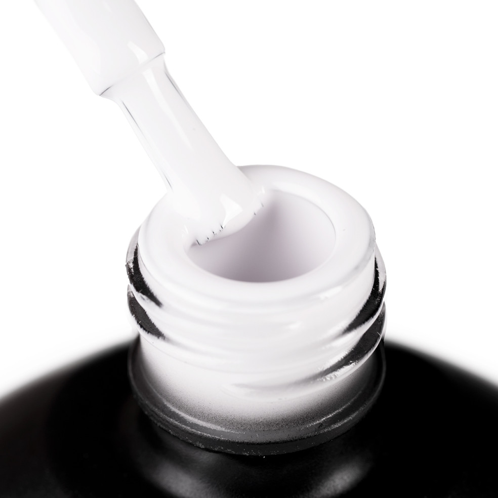 Szyjka butelki i oparty o nią pędzelek zanurzony w mlecznym białym lakierze hybrydowym