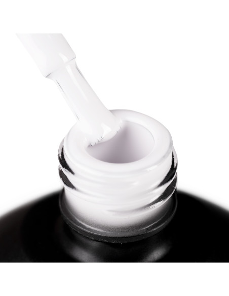 Szyjka butelki i oparty o nią pędzelek zanurzony w mlecznym białym lakierze hybrydowym