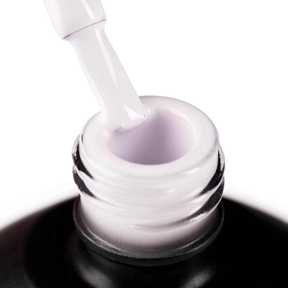 Szyjka butelki i oparty o nią pędzelek zanurzony w mlecznym beżowym odcieniu lakieru hybrydowego