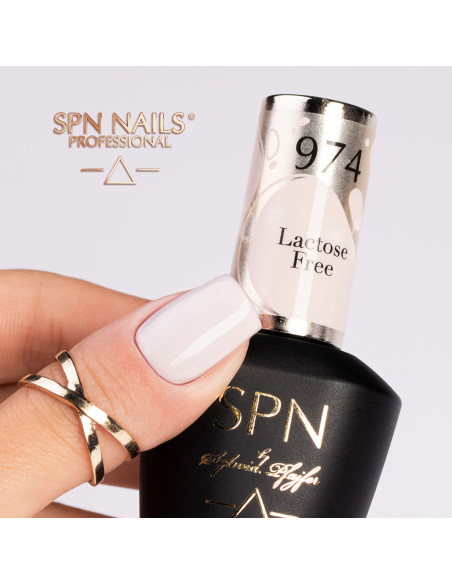 Butelka z lakierem hybrydowym i kciuk pomalowany jasnym beżowym kolorem 974 Lactose Free UV LaQ 8ml
