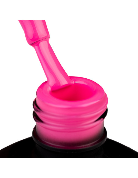 Szyjka butelki i oparty o nią pędzelek zanurzonyw cukierkowo różowym lakierze hybrydowym