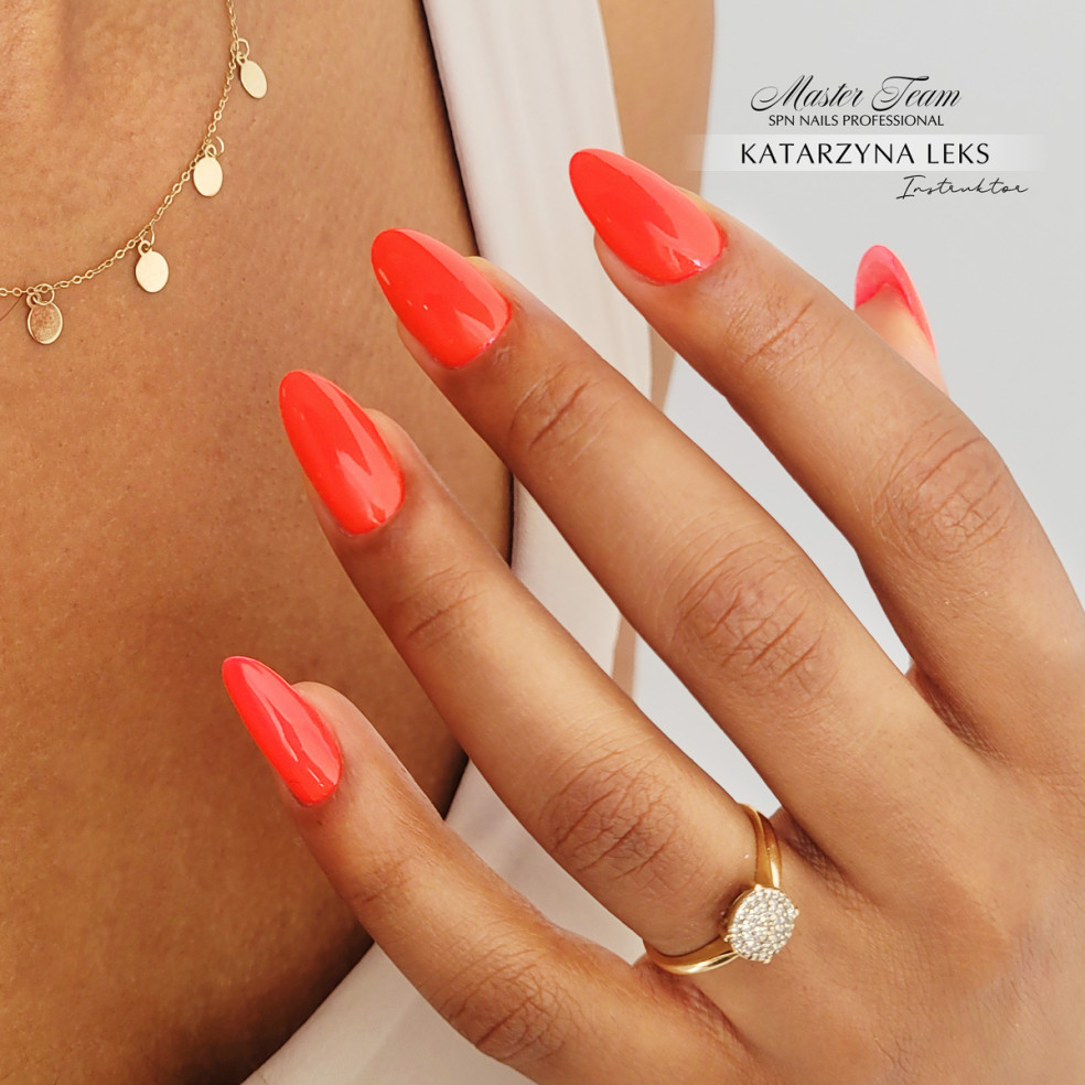 Paznokcie pomalowane nonowym pomarańczowym lakierem.