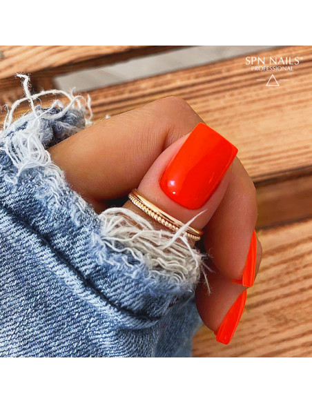 Zbliżenie na kciuk pomalowany neonowym pomarańczowym lakierem hybrydowym