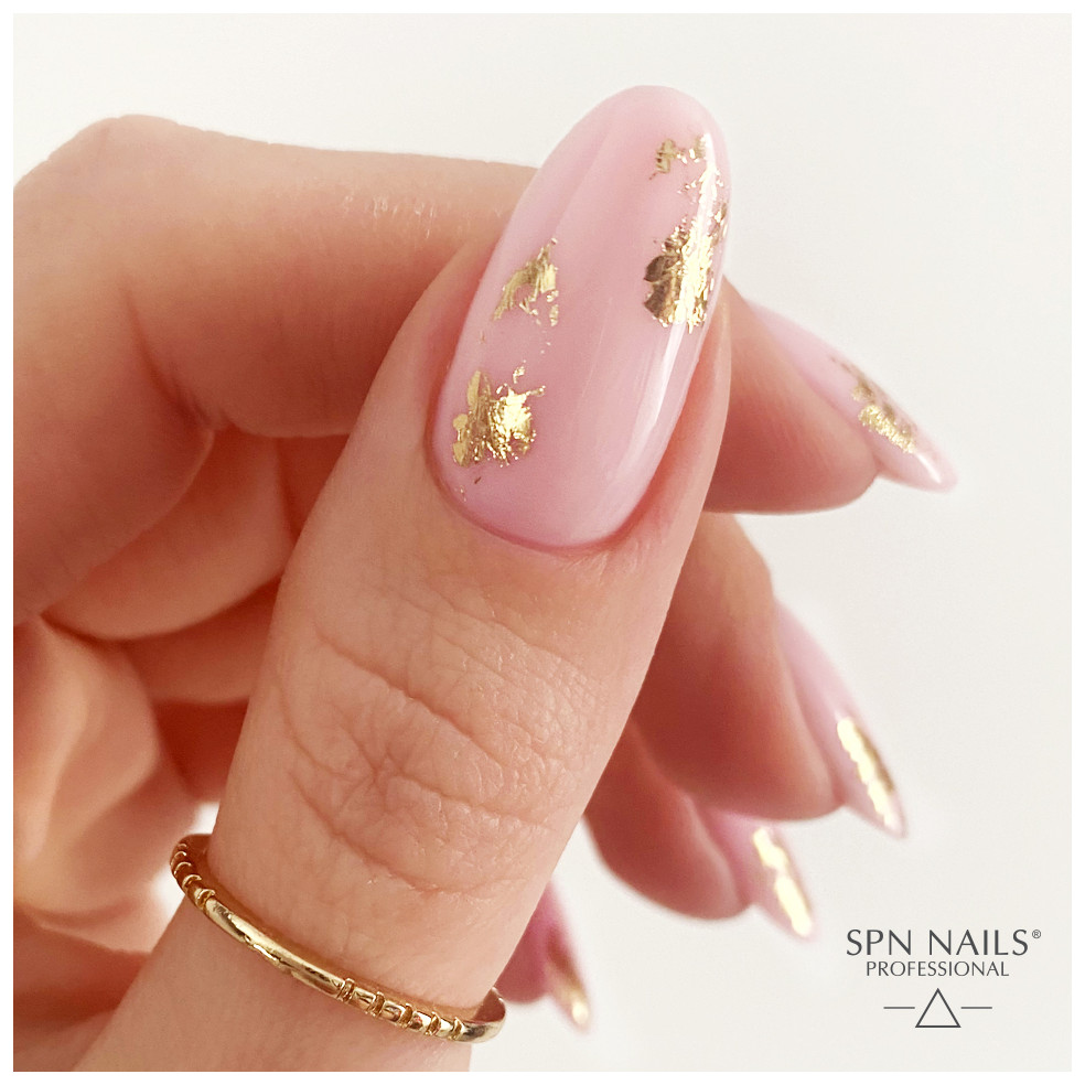 Zbliżenie na kciuk. Paznokcieć pokryty bazą kauczukową w kolorze pudrowego różu Candy Girl Zbliżenie na kciuk. Paznokcieć pokryty bazą kauczukową w kolorze pudrowego różu Candy Girl