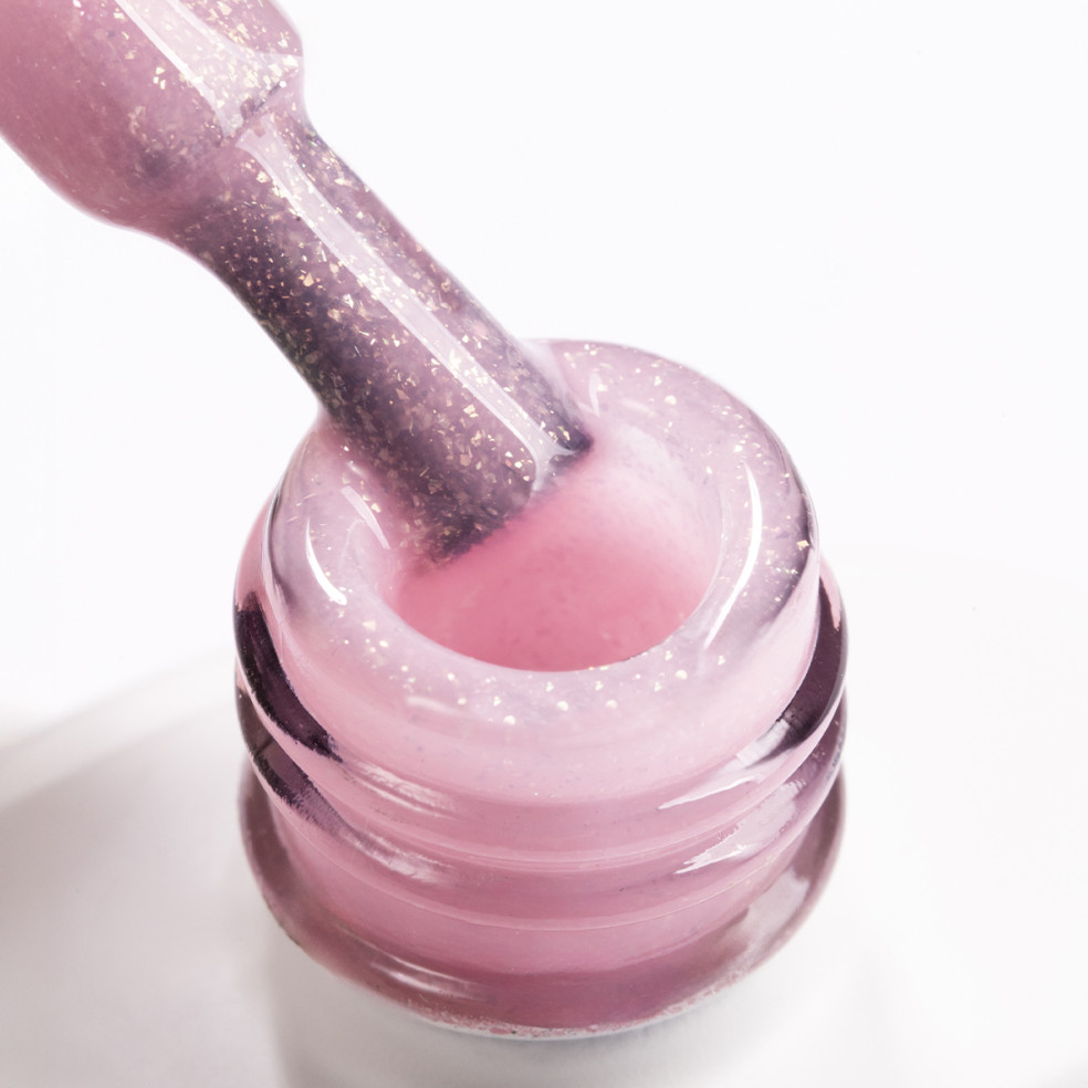 Szyjka butelki i pędzelek zanurzony w różowym żelu do przedłużania paznokci z brokatowymi drobinkami