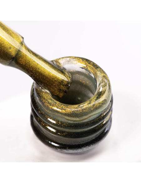 Szyjka butelki i pędzelek zanurzony w złotym lakierze hybrydowym z efektem cat eye Szyjka butelki i pędzelek zanurzony w złotym lakierze hybrydowym z efektem cat eye