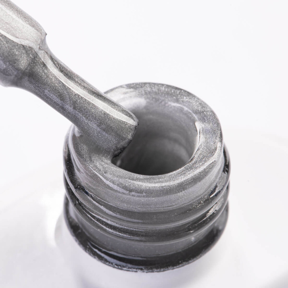 Szyjka butelki i pędzelek zanurzony w srebrnym lakierze hybrydowym z efektem cat eye Szyjka butelki i pędzelek zanurzony w srebrnym lakierze hybrydowym z efektem cat eye