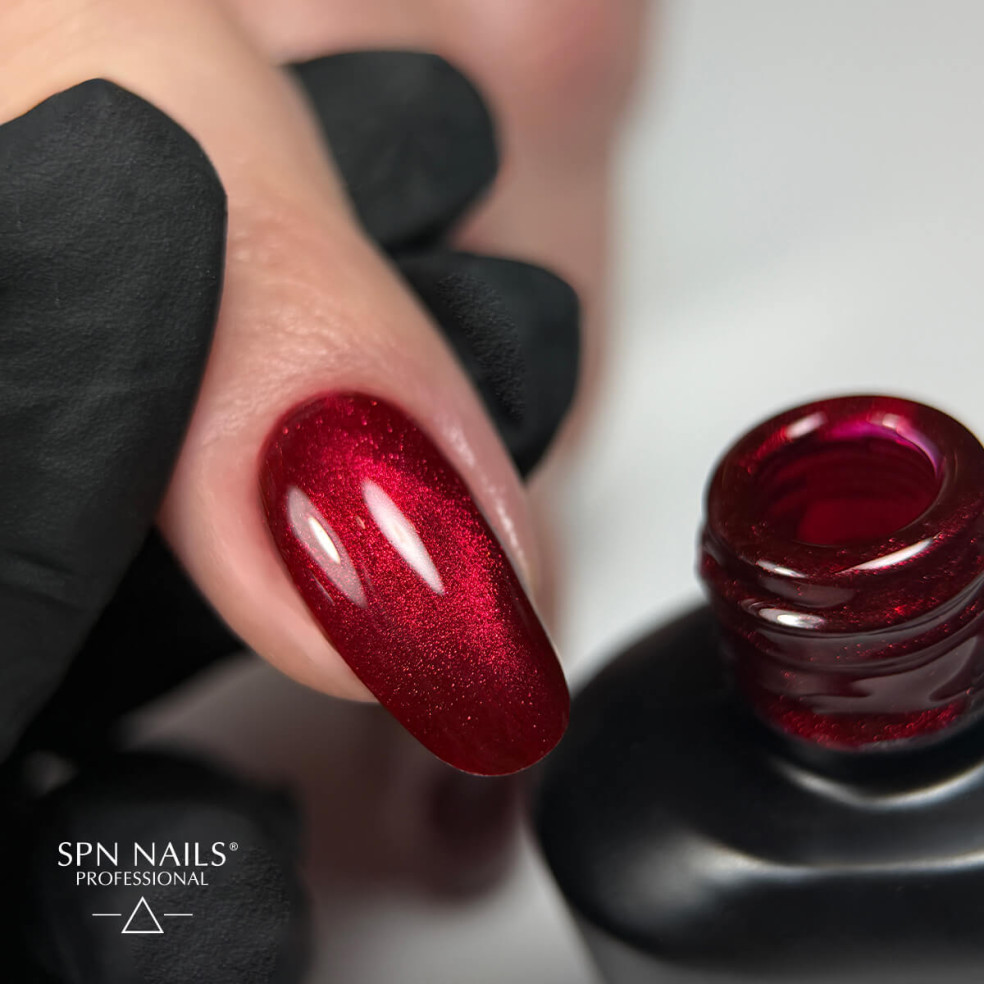 Paznokieć pomalowany czerwonym lakierem hybrdowym Cat Eye z efektem flash