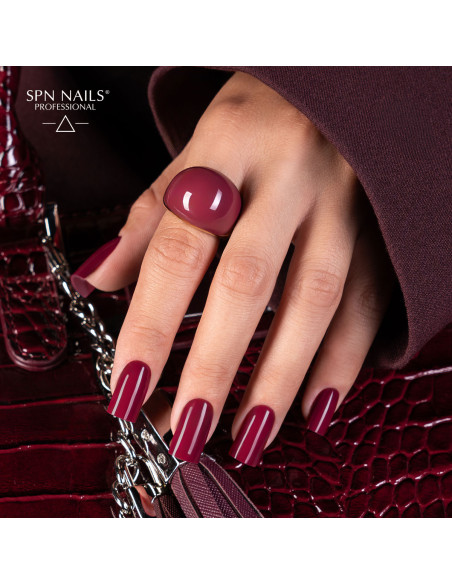 Bordowy manicure lakierem hybrydowym 1044 Guilty Pleasures z zestawu Dark Desires SPN Nails na dłoni trzymającej torebkę