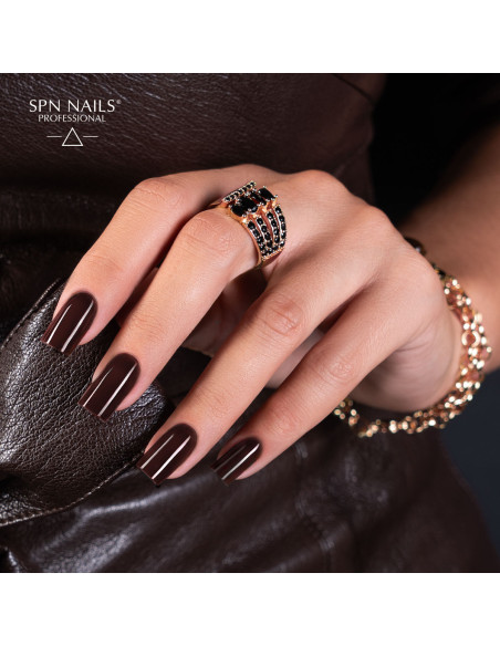 Brązowy manicure lakierem hybrydowym 1046 Deep Desire z zestawu Dark Desires SPN Nails na dłoni ze złotą biżuterią