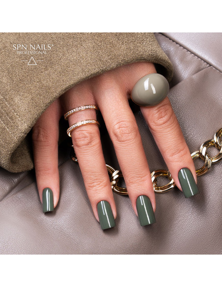 Zielony manicure lakierem hybrydowym 1047 Scandalous z zestawu Dark Desires SPN Nails na dłoni ze złotymi pierścionkami