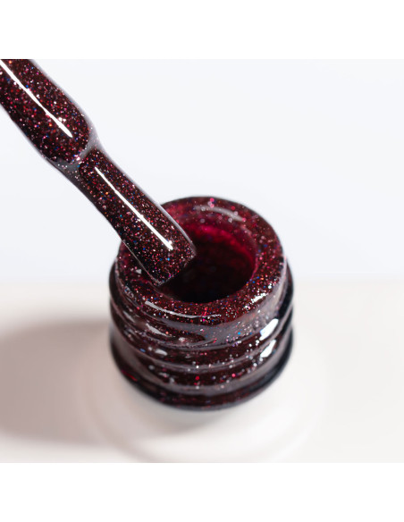 Zbliżenie na pędzelek lakieru hybrydowego NaiLac Sparkleholic ukazujące malinowy róż z brokatem i efektem flash
